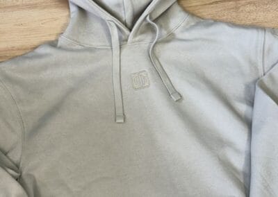 Gemütlicher grauer Hoodie auf Holzfußboden, ideal für kalte Tage. Perfekte Kombination aus Stil und Komfort.